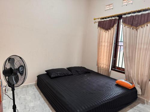 a bedroom with a bed and a fan and a window at NADELS HOMESTAY SYARIAH in Gadut