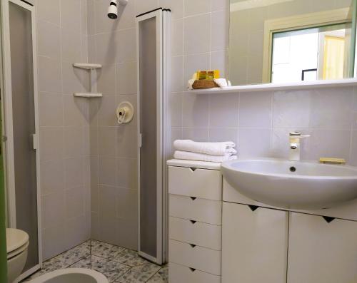 bagno bianco con lavandino e servizi igienici di B&B Casa Corbezzolo a Procchio