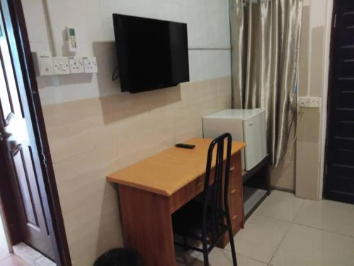 een kleine kamer met een tafel en een televisie aan de muur bij OYO 90972 Jj Homestay in Miri
