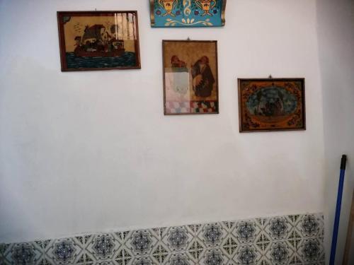 four pictures on a white wall with paintings on it at Maison de ville sousse in Sousse