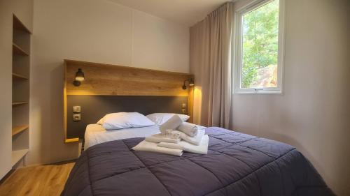 - une chambre avec un grand lit et des serviettes dans l'établissement Vacances en Chalet ou Mobil-home chez Camp'in Pirellu, à Porto-Vecchio