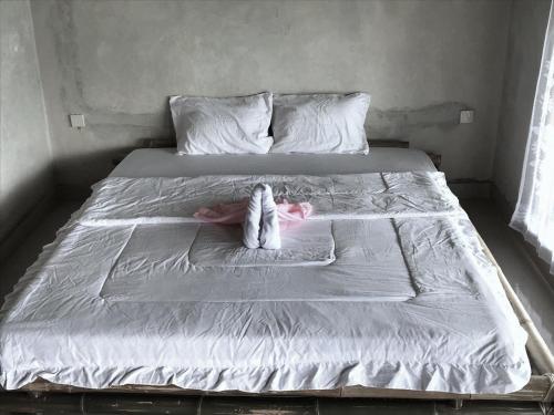 a white bed with two stuffed animals on it at Melody Surf Camp - Ekas Lombok in Ekas