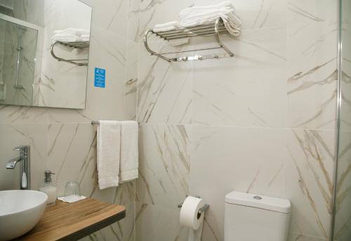 a bathroom with white marble walls and a sink and a toilet at Nova Delpa AL in Caldas da Rainha