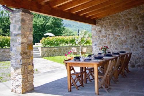 a wooden table and chairs under a stone wall at Locanda Fermento in Mochignano