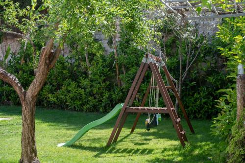 a swing set in a yard with a tree at Lilium Villa, summer aroma, By ThinkVilla in Perama