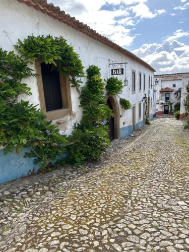 een geplaveide straat voor een wit gebouw bij Casa do Poço in Óbidos