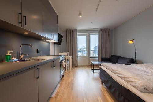 a room with a bed and a kitchen with a sink at Uppsala Hotel Apartments in Uppsala