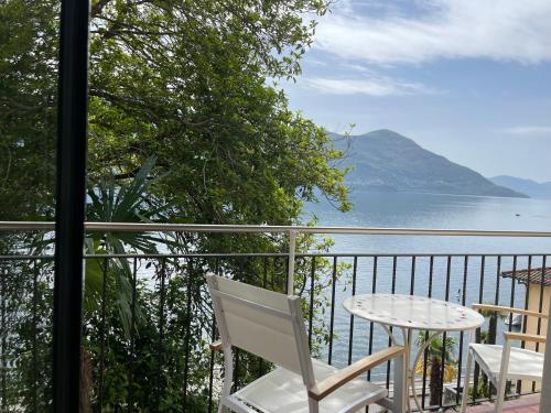 a white chair and table on a balcony with a view of the water at Residenza Bettina BnB & Ferienwohnungen in Ronco s/Ascona - Porto Ronco