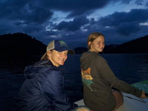 two women sitting on a boat in the water at Lakefront Cabin Bordering Nat Park with Hot Tub! cabin in Turtletown