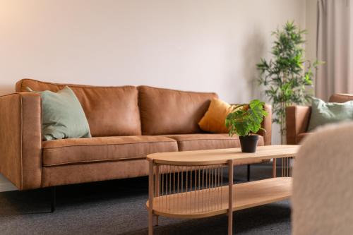 a living room with a brown couch and a table at Uppsala Hotel Apartments in Uppsala