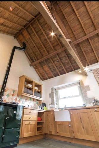 a large kitchen with wooden cabinets and a window at Haytor Rocks, Dartmoor escape in Bovey Tracey