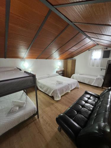 Habitación con 2 camas y sofá. en Villa El Pedregal - Parque Sierra de las Nieves, en Yunquera