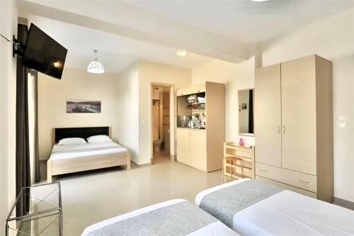 a bedroom with two beds and a tv in it at GREEK PRIDE PANTHEA STUDIOS in Skala Fourkas
