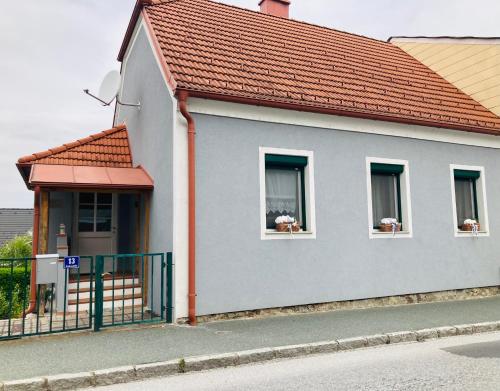 a house with two windows with flowers in them at Das Ferienhaus-zurück zum Ursprung in Güssing