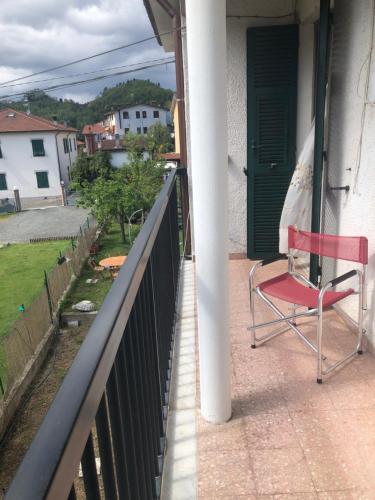a red chair sitting on the balcony of a house at La Primula Vicinanza 5 Terre in Riccò del Golfo di Spezia