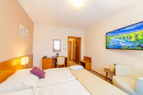 a bedroom with a bed and a tv on the wall at Kontakt Wellness Hotel in Tatranská Lomnica