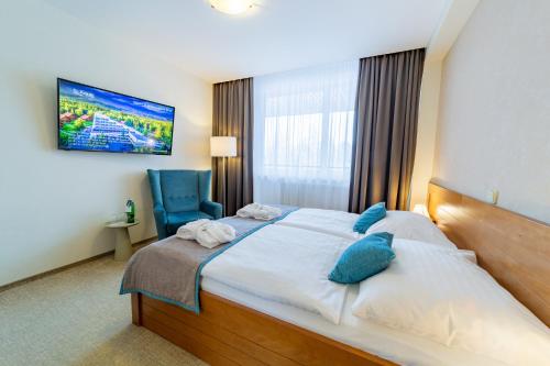 a hotel room with a bed and a blue chair at Kontakt Wellness Hotel in Tatranská Lomnica