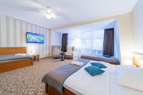 a hotel room with two beds and a tv at Kontakt Wellness Hotel in Tatranská Lomnica