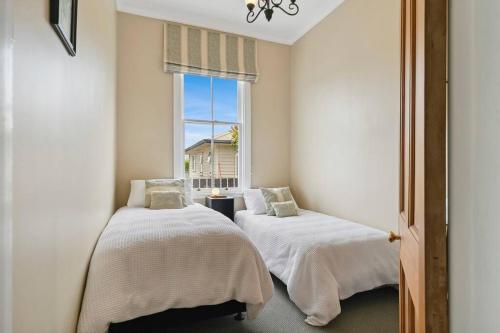 deux lits dans une chambre avec une fenêtre dans l'établissement Historic Charm in Greytown - Tranquil setting - walk to town, à Greytown