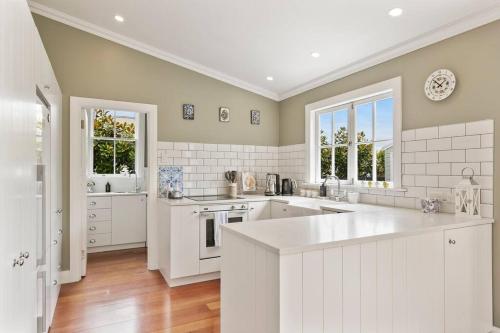une grande cuisine avec des armoires et des fenêtres blanches dans l'établissement Historic Charm in Greytown - Tranquil setting - walk to town, à Greytown