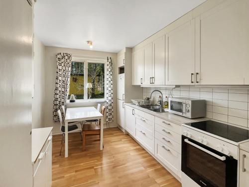 una cocina con armarios blancos y una mesa. en Equipped Apartments, Perfect For Workers, 