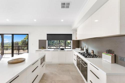 cocina con armarios blancos y fogones en The Lux Country Retreat - heated swimming pool - immaculate views and stylish comfort!, en Port Lincoln