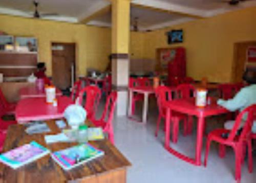 ein Zimmer mit roten Tischen und roten Stühlen in einem Klassenzimmer in der Unterkunft ATITHYA GUEST HOUSE in Srī Niketan