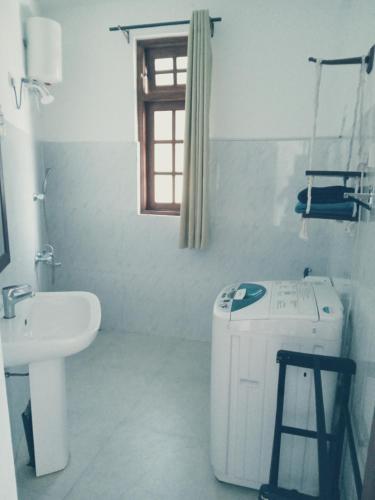 a white bathroom with a sink and a toilet at Metro Stay in Kurunegala