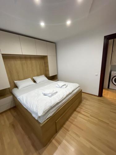 1 dormitorio con 1 cama grande con sábanas blancas en Central Cozy Apartament Near Monastery, en Suceava
