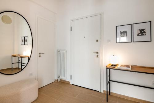 Sunny 2BR Apartment in Nea Smyrni by UPSTREET في أثينا: غرفة معيشة بيضاء مع مرآة وطاولة