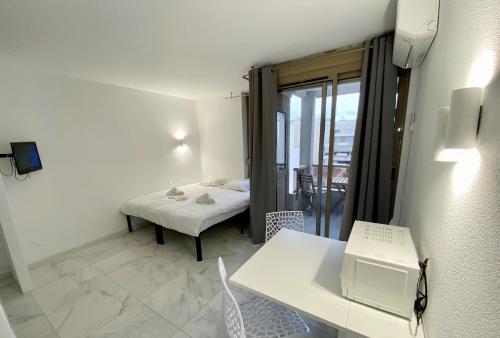 Cette petite chambre blanche comprend un lit et une table. dans l'établissement Résidence Graziella Studio 405, à Juan-les-Pins