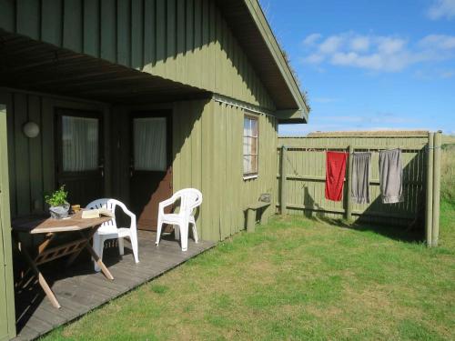 zielony dom ze stołem i krzesłami na patio w obiekcie Scenic Holiday Home In Skagen, w mieście Skagen