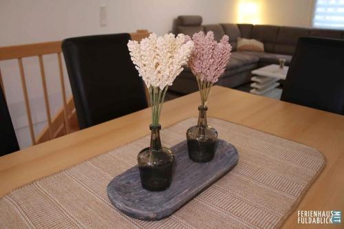 two vases with flowers in them on a table at Ferienhaus Fuldablick in Rotenburg an der Fulda
