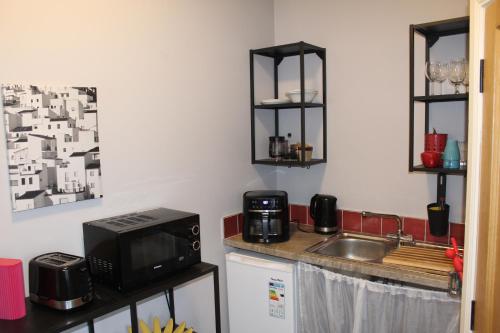 a small kitchen with a sink and a microwave at Studio flat - An Bonnan Bui in Rathmullan