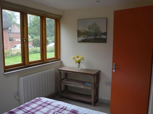 a bedroom with a bed and a table with flowers on it at The Potting Shed Sopley in Christchurch