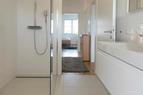 ein weißes Bad mit einer Dusche und einem Waschbecken in der Unterkunft Panoramablick Dobl in Dobl-Zwaring