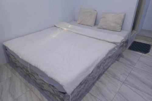 テガルにあるOYO 93900 Guest House Cinta Damaiの白いシーツと枕が備わる客室のベッド1台分です。