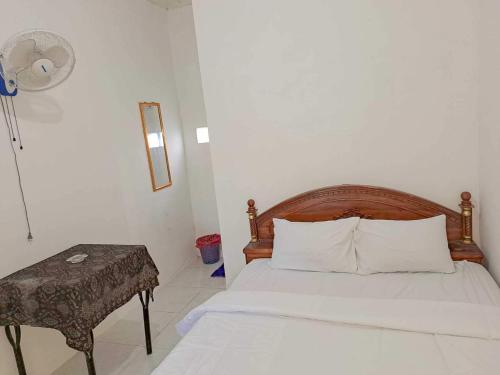 OYO 93902 Guest House Pahlawan Syariah في Kotabumi: غرفة نوم بسرير وطاولة ومروحة
