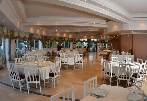 un salón de banquetes con mesas blancas y sillas blancas en Kırtay Hotel Erdek en Erdek