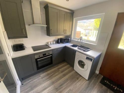 a kitchen with a sink and a washing machine at Tummel View Pitlochry in Pitlochry