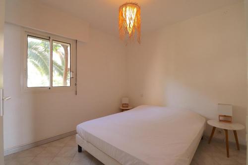 une chambre avec un lit, une fenêtre et un lustre dans l'établissement T2 ARIA MARINA Route des Sanguinaires, Vue MER, Terrasse , Parking, Plage à 50M - 4pers, à Ajaccio