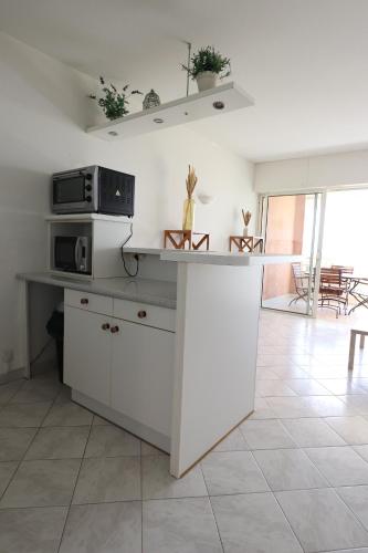 - une cuisine avec un îlot blanc dans une chambre dans l'établissement T2 ARIA MARINA Route des Sanguinaires, Vue MER, Terrasse , Parking, Plage à 50M - 4pers, à Ajaccio