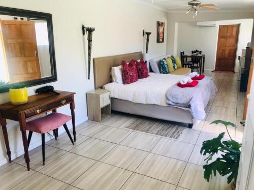 a bedroom with a bed and a table and a mirror at Toni's Cottage in Graaff-Reinet