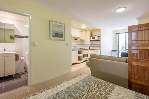a living room with a couch and a kitchen at Convenient Studio With Courtyard in Sydney