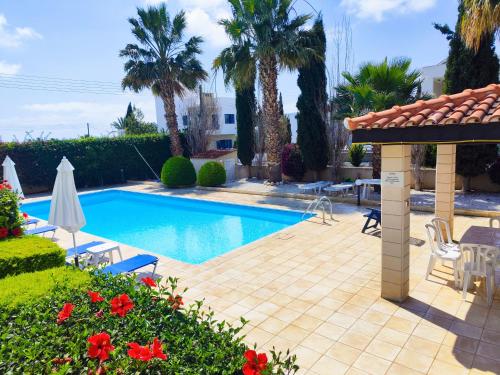 a swimming pool in a yard with palm trees at Sunset Green 01 in Paphos City