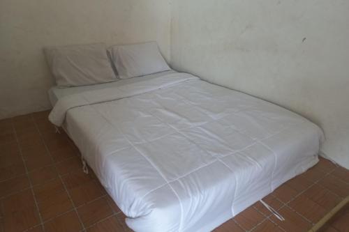 a white bed in a corner of a room at SPOT ON 93917 Homestay Adreena Syariah in Purwokerto