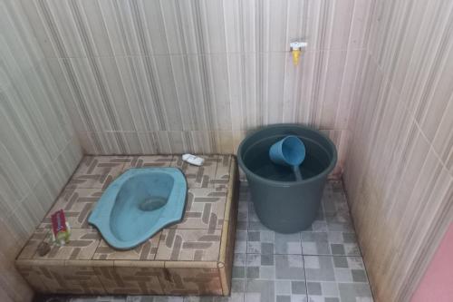 Baño pequeño con aseo azul y cubo de basura en SPOT ON 93917 Homestay Adreena Syariah en Purwokerto