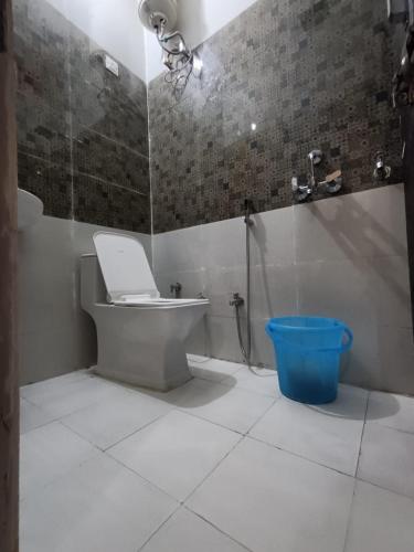 a bathroom with a toilet and a blue bucket at Hotel JP Inn in Lucknow