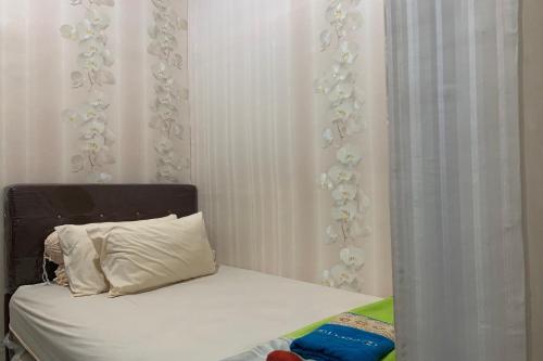 a bed with a black headboard and a white curtain at OYO 93918 Wisma Tulip 
