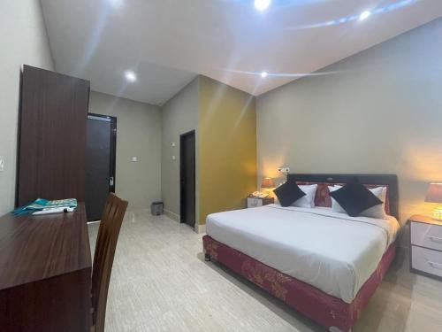 a bedroom with a bed and a table and a desk at Aislah Edotel Lombok in Sakra
